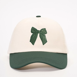 Dettaglio del ricamo a fiocco verde su questo cappellino da baseball bicolore