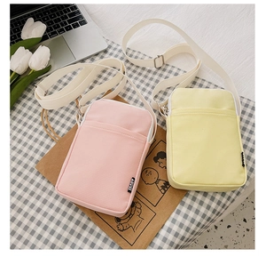 Detail of pink and yellow canvas mini crossbody bags with sport label and woven strap