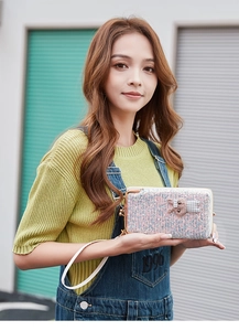 Detail of silver glitter wallet with kiss lock and cute animal charm held by a woman