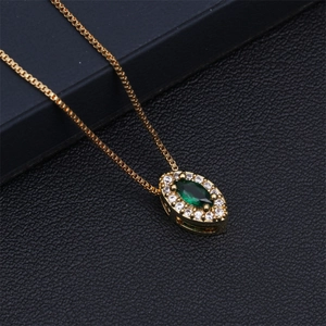 Detail of a gold necklace with a green teardrop stone and zircon on black leather
