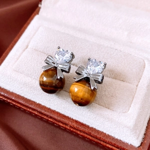 Macro detail of heart-shaped zircon, bow-knot and tiger eye stone drop on retro earrings