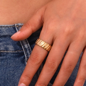 Detailed view of 18K gold plated textured ring worn on hand over blue denim fabric