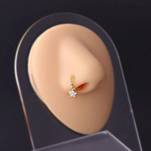Macro detail of a 20G gold nose ring with a zircon star pendant on a display model
