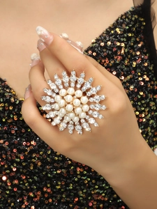 Dettaglio di un grande anello floreale boho con perle e strass sulla mano della modella