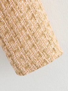 Close-up of beige and pink tweed fabric with metallic gold thread and woven texture