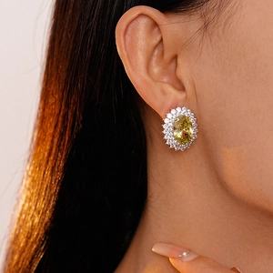 Close-up of elegant oval yellow zircon stud earrings worn by a model in soft lighting