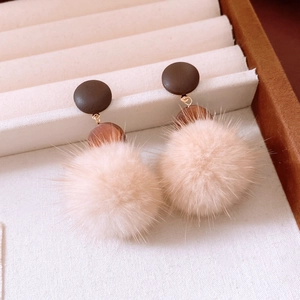 Macro view of vintage round fur ball earrings with wooden beads and silver pins