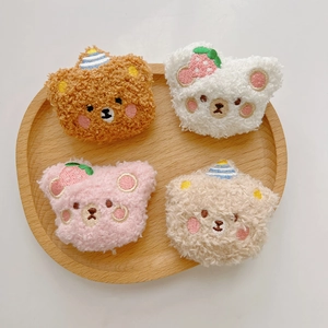 Plush cartoon bear brooches in brown, white, and pink on a round wooden tray