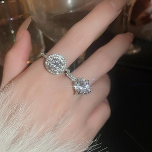 Close-up of stacked silver rings with zircon stones worn against a soft fur background