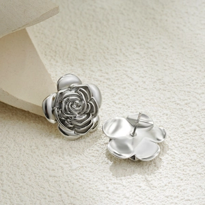 Detailed macro view of 18K gold rose stud earrings with silver flower petal textures