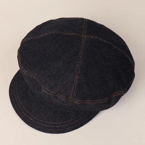 Detail of dark blue denim newsboy cap with contrasting orange stitching and twill texture
