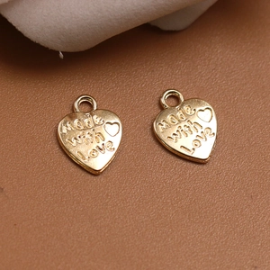 Primer plano de dijes de corazón grabados Made with Love sobre una base de cuero café