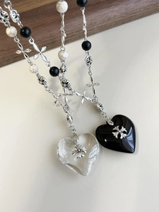 Close-up of gothic heart pendants with cross engravings and stone beaded chain