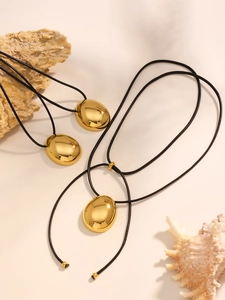 Detailed view of polished oval pebble pendants on black cords with natural stone decor