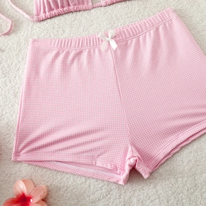 Detail of pink gingham bikini shorts with white satin bow on soft plush background
