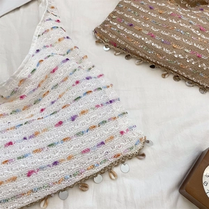 Detail of crochet knit top featuring colorful stripes, sequins and shell fringe tassels