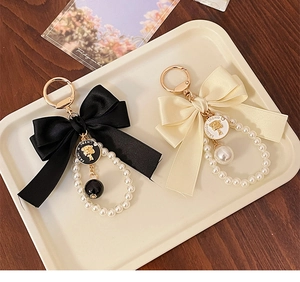 Detail of elegant ribbon bow keychain with pearl ring and gold fashion pendant charm