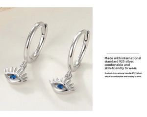 Macro view of 925 silver evil eye hoop earrings with a blue gemstone and radiant metal lines