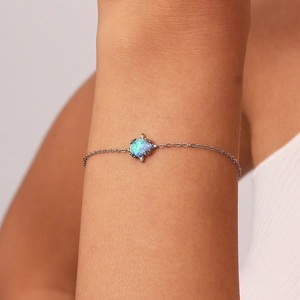 Delicate teardrop opal bracelet detail shot featuring a vibrant blue gemstone on fine silver chain.