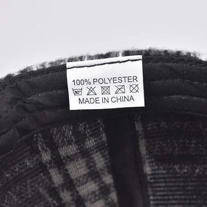 Detailed close-up of the plaid baseball cap interior showing the 100% polyester care label