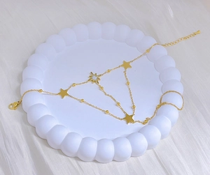 Detailed view of a gold star and north star charm bracelet on a white tray