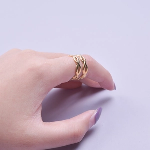 Detail view of a golden double-layered twisted rope ring worn on finger with purple background
