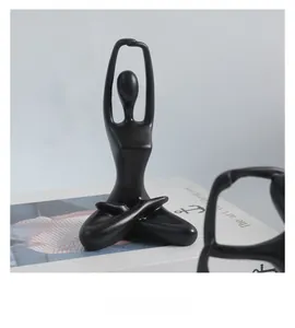 Close-up of black matte ceramic yoga pose figurine with modern abstract artistic texture