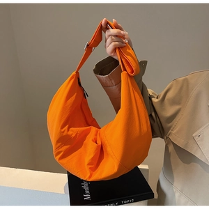 Detail of a bright orange nylon crescent bag with adjustable wide shoulder strap