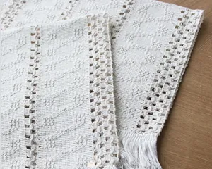 Close-up of Nordic style cream lace placemat with crochet details and tassels