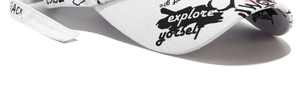 Close-up of graffiti lettering on the curved brim of a white cotton baseball cap