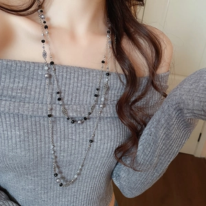 Detail of layered floral pearl sweater necklace on a grey knit sweater for women