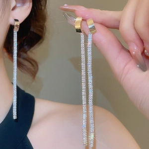Detailed close-up of gold tassel earrings with cubic zirconia stones on model