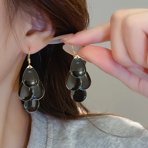 Close-up of elegant black enamel triple teardrop tassel earrings with gold-plated edges