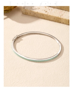 Detail of silver bangle with mint green enamel inlay and spring buckle on stone texture