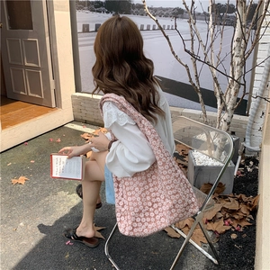 Detailed side view of a pink canvas tote bag with white daisy floral embroidery pattern