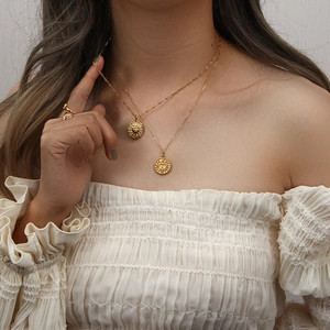 Gros plan d'un collier doré double épaisseur avec pendentifs soleil en relief