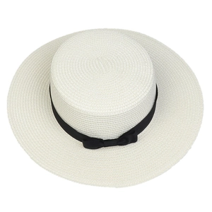 Top view of white straw boater hat with black ribbon and bow detail texture