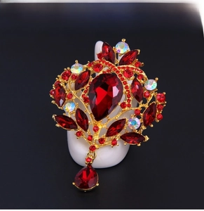 Close-up of vintage gold hollow brooch with deep red crystals and teardrop pendant