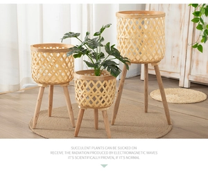 Three-tier woven bamboo plant stand set with wooden legs in a minimalist interior setting