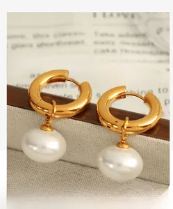 Macro shot of gold hoop earrings with white pearl pendants on vintage magazine background