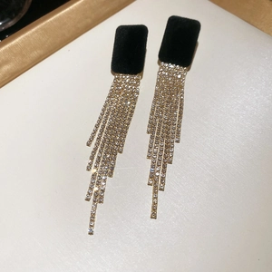 Dettaglio degli orecchini quadrati in velluto nero con lunghe nappe di strass brillanti