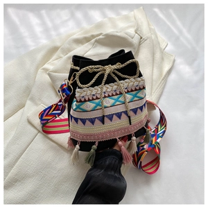 Detail of bucket bag with bohemian embroidery, colorful tassels and golden rope drawstring