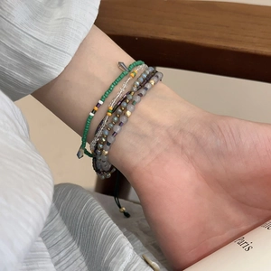 Detail of bohemian layered beaded bracelet with green and purple crystal beads on wrist