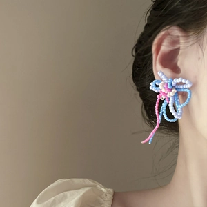 Detail of colorful beaded flower earrings with fringe tassels worn by a model
