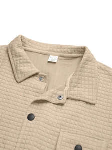 Detail of khaki quilted shirt jacket neckline with diamond pattern and button snaps