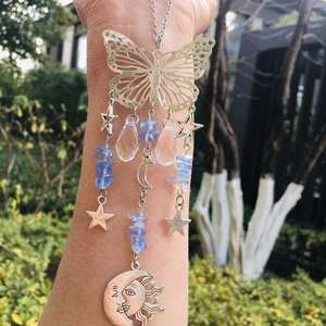 Detail of silver butterfly suncatcher with blue crystal beads and moon charm in sunlight