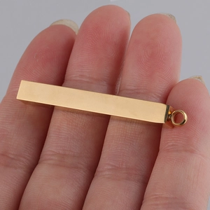Detailed view of a 5x40mm golden mirror-polished stainless steel bar pendant held by fingers
