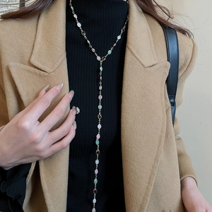 Detailed close-up of a gold Y-shaped necklace featuring purple and green oval gemstones