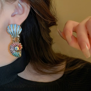 Detailed close-up of vintage gold shell and conch earrings with colorful rhinestones