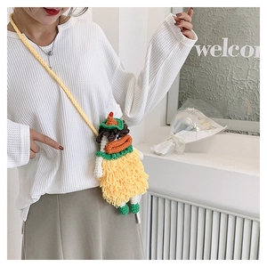 Detail of yellow handmade knit duck crossbody bag with green hat and funny red sausage lips